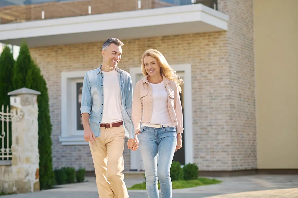 Refinancing - happy couple walking in front of house